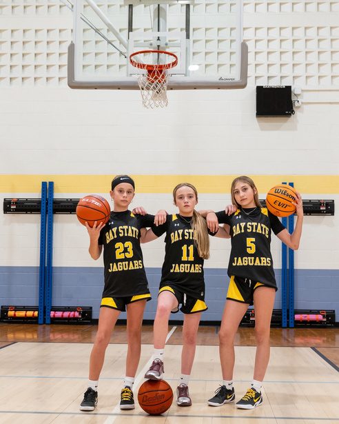 Three basketball players posing on the court