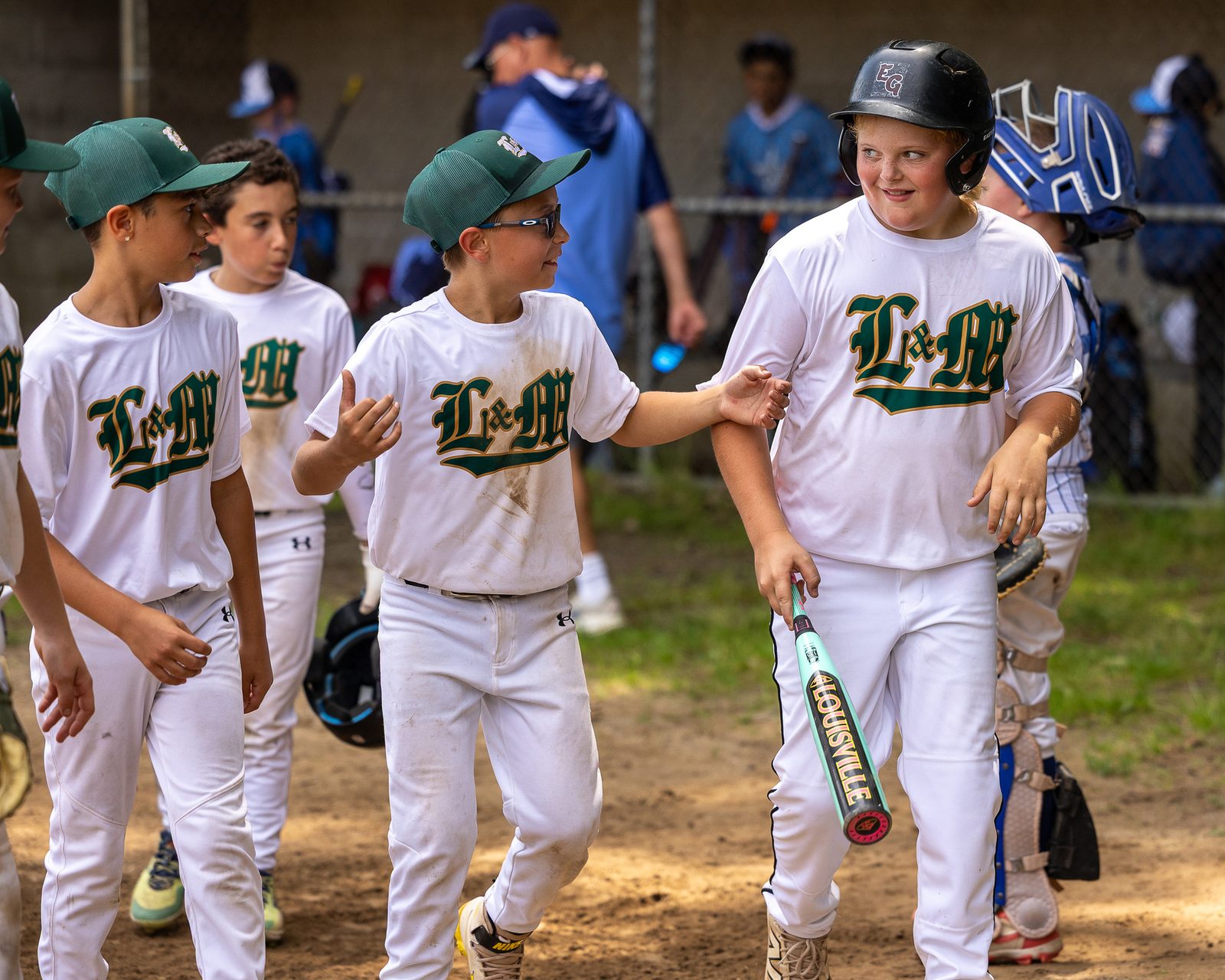 Youth baseball players in white uniforms walking off the field together